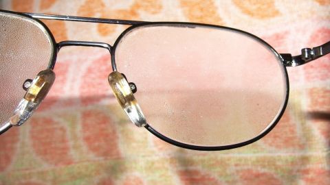 Eine Brille mit klaren Gläsern liegt auf einem farbigen, gemusterten Hintergrund, der eine entspannte Atmosphäre schafft.