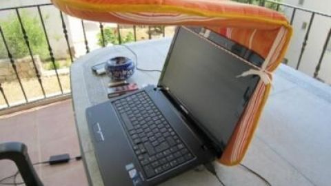 Ein Notebook steht auf einem Tisch, während ein Sonnenblendenobjekt darüber positioniert ist, um Schatten zu spenden.