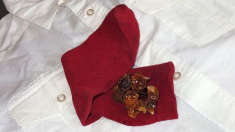 Eine rote Stoffserviette hält eine Mischung aus Waschnüssen, die auf einem weißen Hemd liegen, um schwere Verschmutzungen zu bekämpfen.