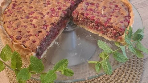 Ein Johannisbeerkuchen, lecker und frisch, steht auf einem Tisch, umgeben von dekorativen Elementen wie Blumen und einer Kerze.
