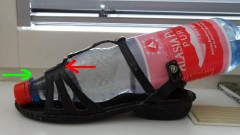 Ein schwarzer Sommerschuh hat eine Wasserflasche als Füllung, die ihn weitet, während er auf einer Fensterbank liegt.