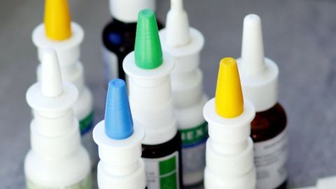 Eine Reihe von Nasensprays steht auf einem Tisch. Die Flaschen variieren in Farbe und Größe, um verschiedene Anwendungen anzuzeigen.