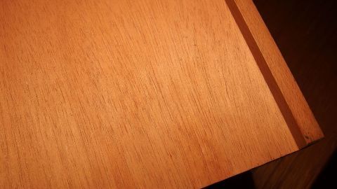 Ein unbehandeltes Holzstück wird sorgfältig abgewischt, um Staub zu entfernen und die Oberflächenpflege zu unterstützen.