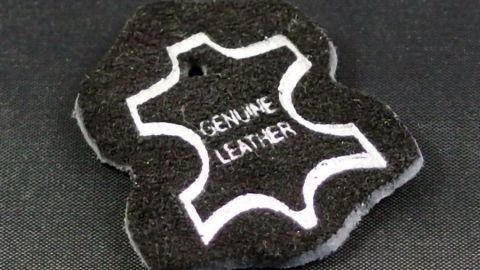 Ein schwarzes Pflegepad in Lederform zeigt den Text „GENUINE LEATHER“, das zur Lederpflege verwendet wird.