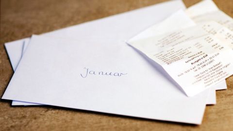 Ein Umschlag mit „Januar“ liegt auf einem Tisch, daneben stecken Kassenzettel, die teilweise sichtbar sind.