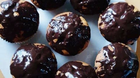 Auf einem Teller liegen frisch gebackene Muffins, die mit Luftschokolade glasiert sind und glänzen.