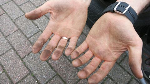 Der Tipp wirkt Wunder und ist von meiner Oma: Ölverschmierte Hände lassen sich hervorragend und gesund mit Speiseöl und Zucker reinigen. Ölverschmierte Hände halten offen, bereit zum Säubern mit Hausmitteln auf einem gepflasterten Boden.