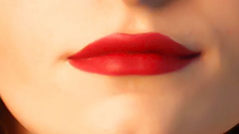 Mithilfe von Lippenkonturenstift und Puder hält dein Lippenstift stundenlang. Rote Lippen mit Lippenstift betonen den Ausdruck, während das Gesicht weich im Hintergrund verschwommen ist.