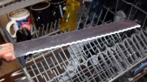 Eine Messerklinge liegt im Geschirrspüler und wird mit anderen Tassen und Gläsern gereinigt.