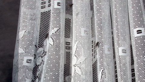 Vor einem Fenster hängen durchsichtige Vorhänge, die Fliegen davon abhalten, ins Zimmer zu gelangen.