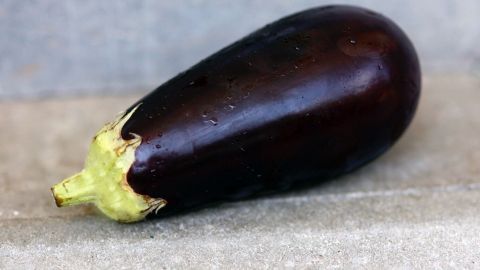 Da bittere Auberginen selten sind, kann man sich das Einsalzen sparen. Man kann stattdessen vor dem Kochen ein winziges Stück Aubergine probieren und so feststellen, ob sie für den Verzehr geeignet ist. Eine glänzende Aubergine liegt auf einer hellen Oberfläche, bereit für die Zubereitung in einem Gericht ohne Salzen.