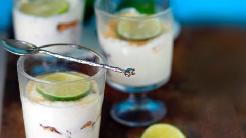 Kühle Gläser mit einem erfrischenden Nachtisch, garniert mit Limettenscheiben, stehen auf einem rustikalen Tisch.