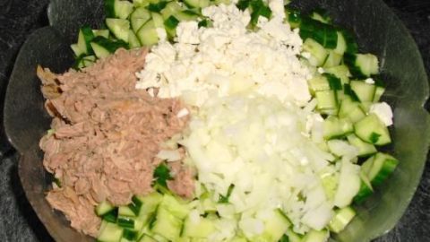 Gurkensalat mit Schafskäse, Thunfisch und Zwiebeln liegt appetitlich in einer Schüssel, bereit zum Servieren.