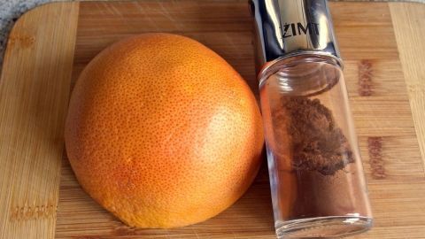 Eine Grapefruit liegt neben einem Gewürzstreuer auf einem Holzbrett, ideal für Tipps gegen Schweißfüße.