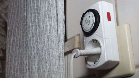Eine Zeitschaltuhr ist an einer Wandmontage installiert und steuert Geräte im Kontext eines Wohnraums.