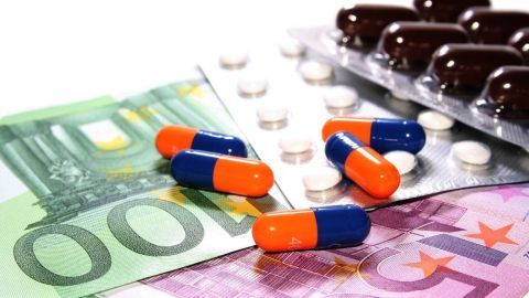 Bunte Kapseln liegen auf Euro-Scheinen und einer Blisterpackung, was das Thema Medikamente und günstigen Einkauf in Holland verdeutlicht.