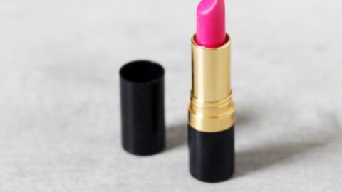 Nicht nur Nagellack hält sich im Kühlschrank länger. Lippenstifte mögen es ebenfalls gern kühl! Ein pinker Lippenstift steht auf einem hellen Untergrund, während die Kappe daneben liegt, bereit zur Verwendung.