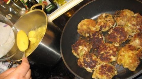Frikadellen braten in einer Pfanne; daneben werden Kartoffeln aus einem Topf gehoben. Im Hintergrund stehen Öle und Gewürze.