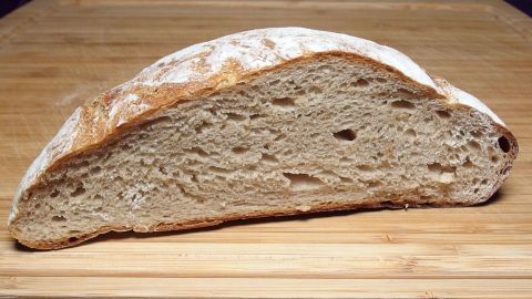 Ein frisch gebackenes Brot liegt auf einem Holzbrett, seine krustige Oberfläche zeigt die handwerkliche Qualität des Backens.