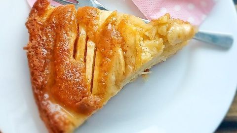 Ein Stück mexikanischer Apfelkuchen liegt auf einem weißen Teller mit einer Gabel, daneben eine pinke Schleife.