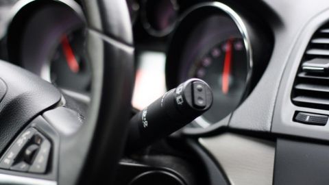 Ein Steuerhebel im Auto aktiviert den Tempomat, während das Cockpit mit verschiedenen Instrumenten ausgestattet ist.