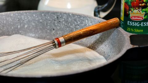 In einer Pfanne mit Zucker und einem Schneebesen wird eine Masse für den Papierkleber aus Milch vorbereitet.