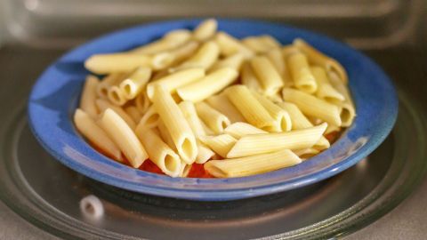 Ein blauer Teller mit ungekochten Röhrennudeln wird in einer Mikrowelle erhitzt, ideal für Sauber Bolognese & Co.