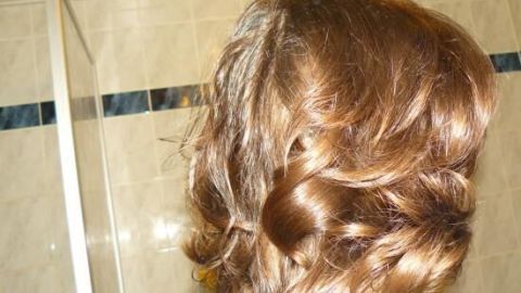 Dichte, durchgestufte Haare werden im Badezimmer geföhnt, glänzend und fast wie frisch vom Friseur.