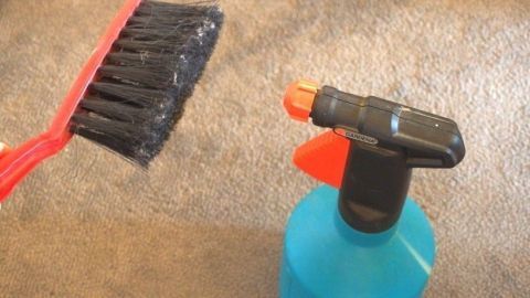 Ohne Staubsauger Staub auf dem Laminat schnell entfernen. Eine Reinigungsbürste und eine Sprühflasche liegen auf dem Laminat, bereit, um Staub zu entfernen ohne Staubsauger.