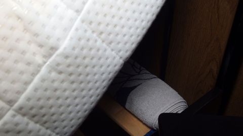 Eine Matratze wird angehoben, während eine Handtuchrolle darunter positioniert ist, um das Bettteil zu erhöhen.