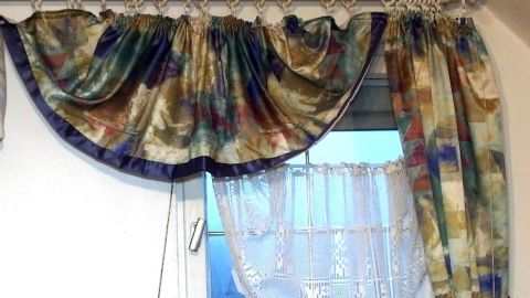 Bunte Gardinen hängen dekorativ am Fenster, bereit zum Waschen in der Waschmaschine, um Frische ins Zimmer zu bringen.