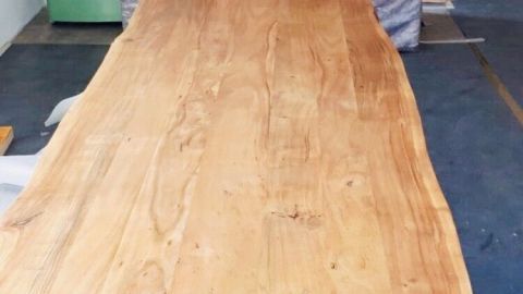 Ein handgefertigter Holztisch wird in einer Werkstatt bewegt, um Wasserflecken auf der Oberfläche zu entfernen.