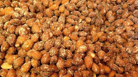 Geröstete Mandeln sind in einer gleichmäßigen Schicht angeordnet, leicht glänzend und ohne dicke Zuckerkruste.