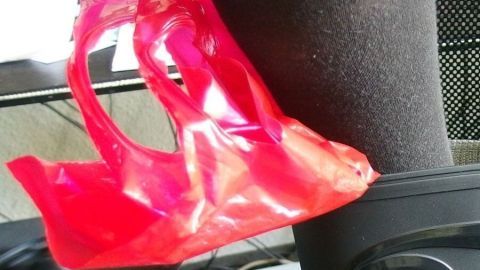 Ein roter Schuhlöffel hilft beim Anziehen eines hohen Stiefels, während ein Bein im Hintergrund sichtbar ist.