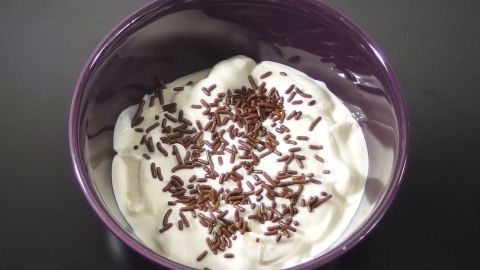 Eine Schüssel Quarkspeise steht auf einem schwarzen Tisch, dekoriert mit Schokoladenstreuseln.
