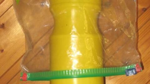 Eine gelbe Plastikflasche wird in einer transparenten Ziplock-Tüte auf einem Holztisch gezeigt, um sie sauber zu lagern.