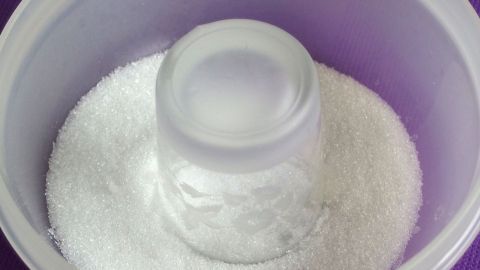 Ein Glas steht verkehrt herum in einer Schüssel mit Zucker, um eine Kruste am Glasrand zu bilden.