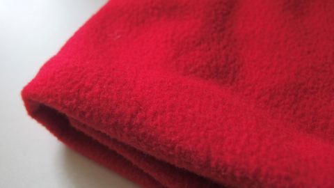 Ein rotes Kuschelfleece liegt gefaltet auf einer hellen Oberfläche, weich und einladend für ein gemütliches Kuschelgefühl.
