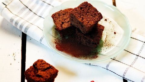 Dunkle Brownies liegen auf einem Teller, umgeben von einem weißen Geschirrtuch, das die rustikale Atmosphäre verstärkt.