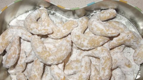 Mürbeteig Vanillekipferln liegen übereinander in einer herzförmigen Dose, staubig mit Puderzucker für das Weihnachtsfest.