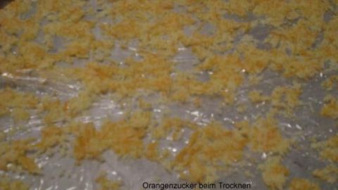 Auf einem Backblech liegt trockener, gelber Orangen- und Zitronenzucker, gleichmäßig verteilt zum Trocknen.