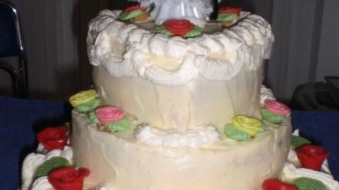 Eine mehrstöckige Hochzeitstorte mit Schokoladensahne, dekoriert mit buntem Zuckerguss und einer Brautpaarfigur oben.