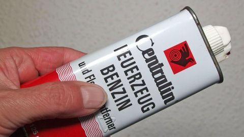 Eine Hand h&auml;lt eine Dose mit Feuerzeugbenzin, die zur Entfernung von Kleberesten von der Haut verwendet wird.