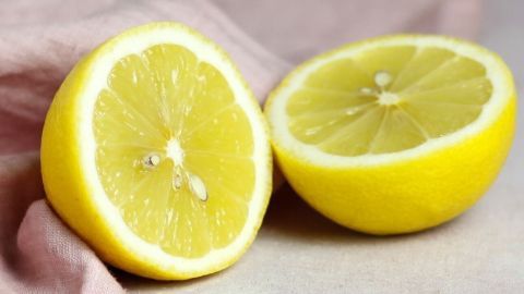 Zitronenhälften liegen auf einer weichen Oberfläche und scheinen frisch geschnitten, bereit zur Reinigung und Pflege der Hände.
