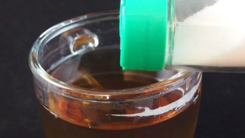 Ein Glas Tee wird mit Salz aus einem Streuer gewürzt, um die durchfallbedingten Beschwerden zu lindern.