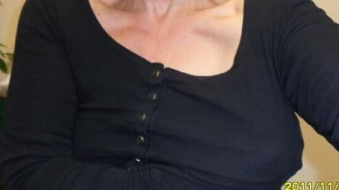 Schwarzes Oberteil mit Knöpfen, das eine Person trägt, deren Haut sichtbar ist, um Deoflecken zu vermeiden.