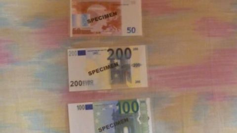Drei laminierte Geldscheine in Euro liegen auf einem bunten Hintergrund, um Stabilität und Schutz vor Abnutzung zu zeigen.