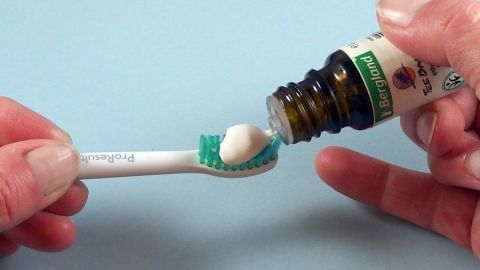Eine Zahnbürste wird mit Teebaumöl befüllt, um gelbe Zähne zu bekämpfen und sie weißer zu machen.
