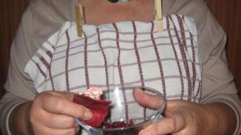 Ein Küchentuch dient als Spritzschutz, während eine Person eine Schüssel hält und mit einem Löffel die Speisen anrichtet.