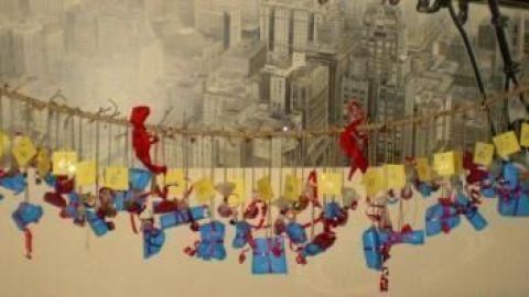 Ein dekorativer Adventskalender hängt an einer Schnur, gefüllt mit bunten Päckchen, vor einer Wand.
